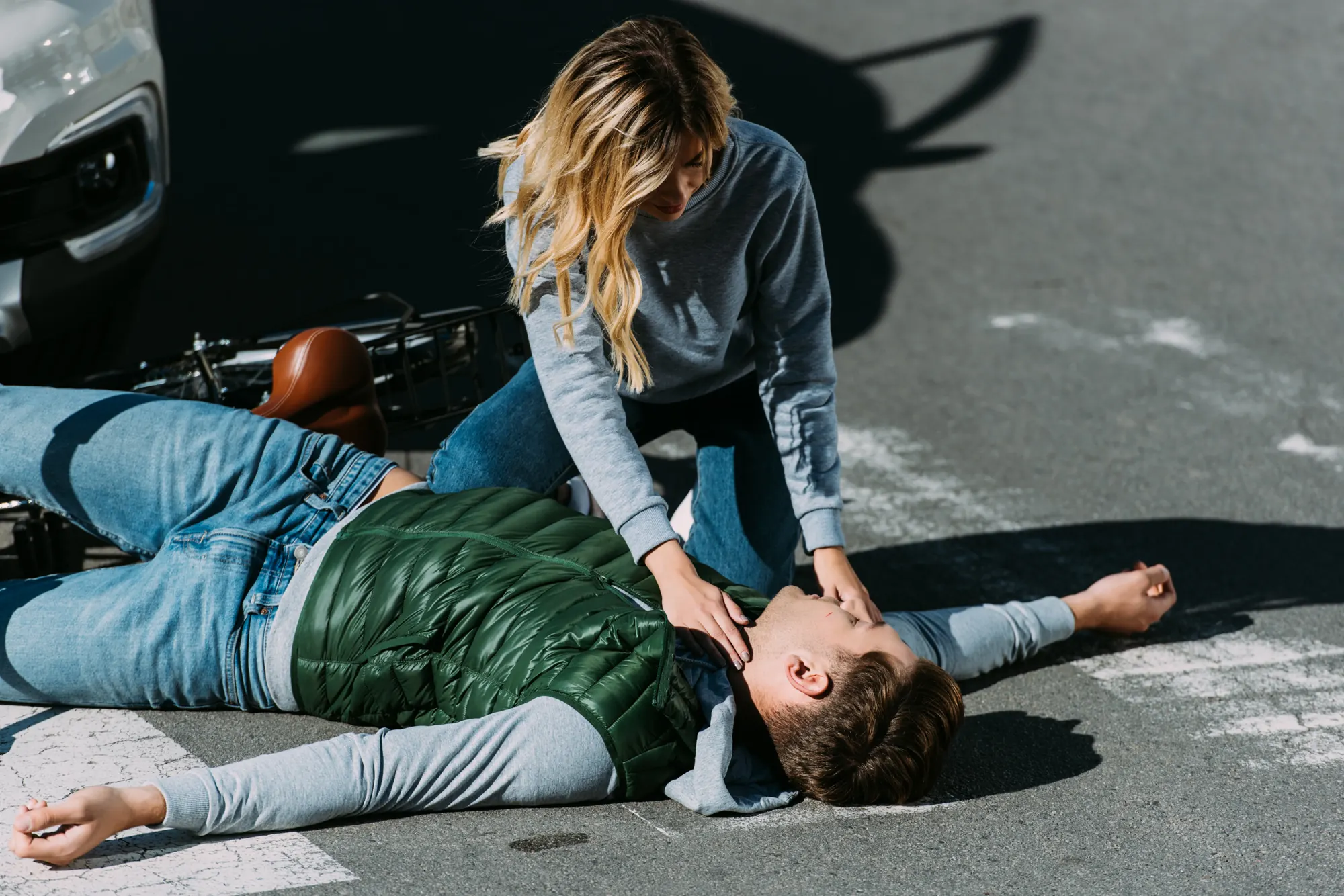 Woman assisting an injured man lying in the street after a traffic accident
