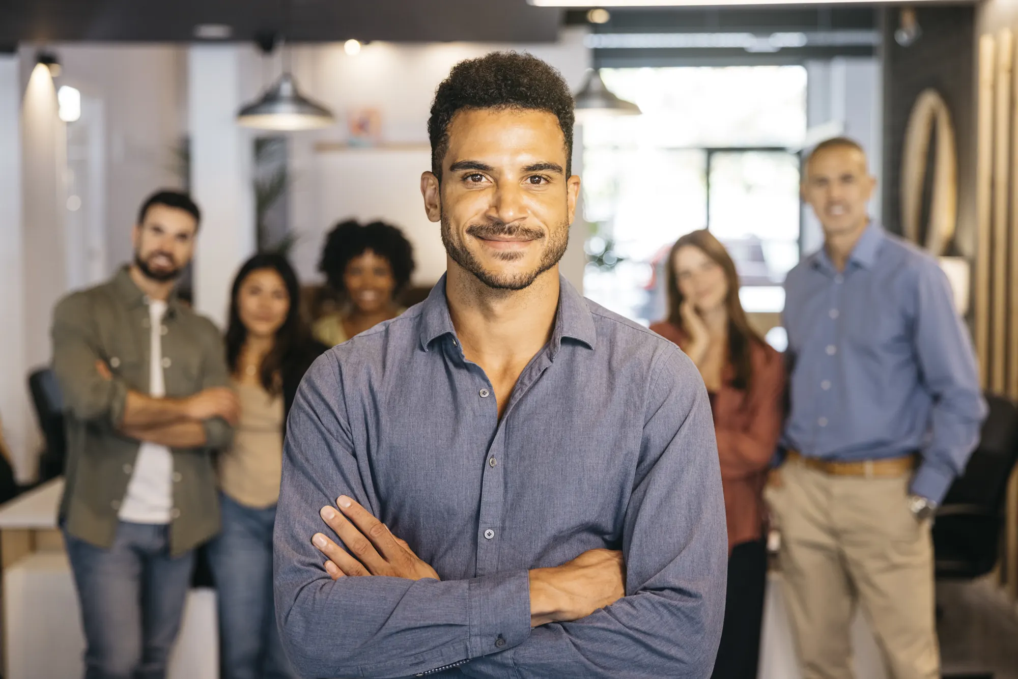 Smiling man with arms crossed in front of his team